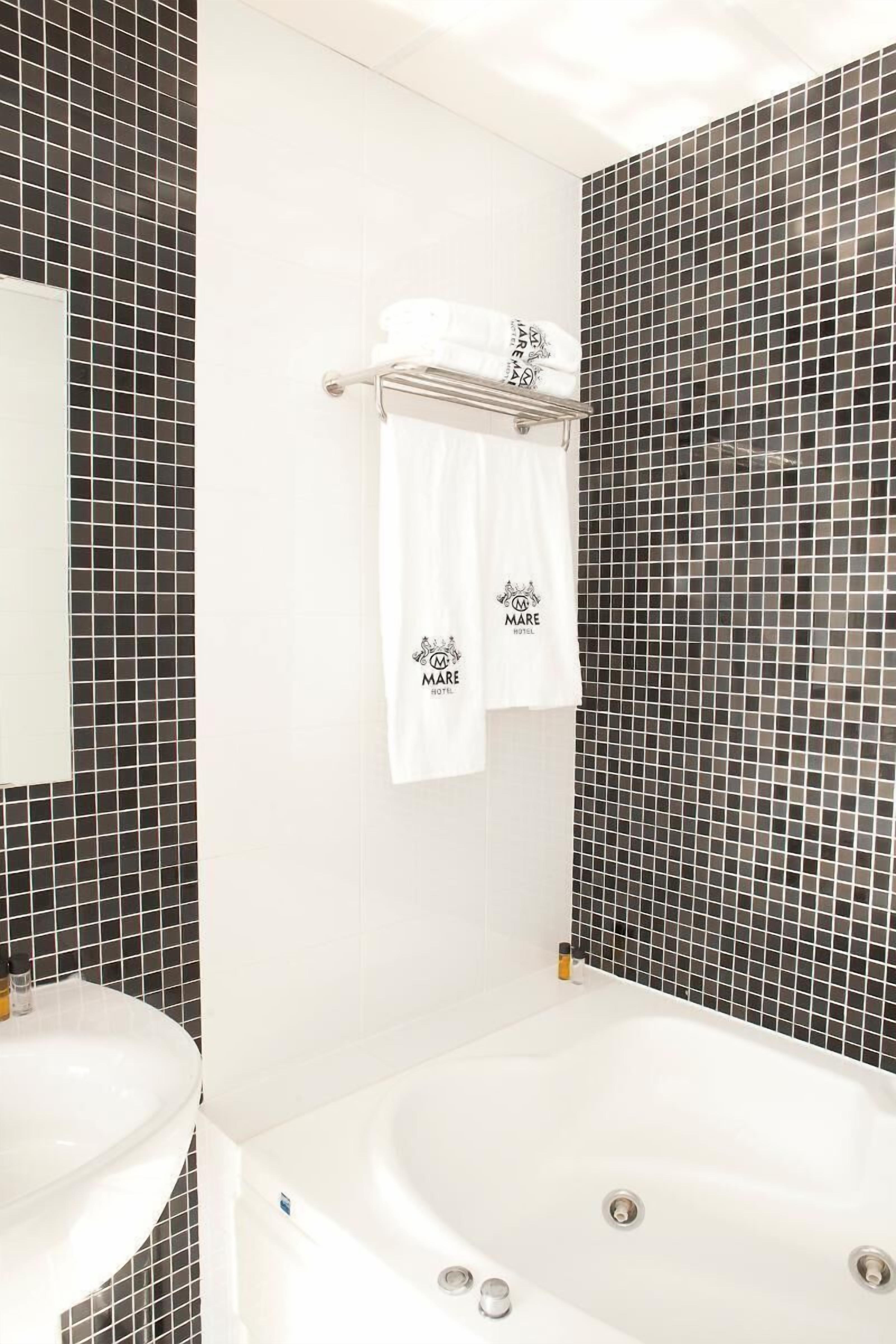 A bathroom with a white sink, a bathtub, and a towel rack with two towels hanging.