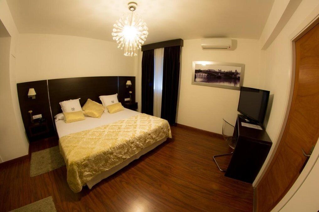 Une chambre d’hôtel avec un grand lit, une télévision, une table de chevet et un climatiseur fixé au mur.