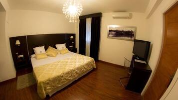 Une chambre d’hôtel avec un grand lit, une télévision, une table de chevet et un climatiseur fixé au mur.