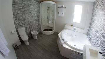 A modern bathroom with a glass-enclosed shower, a freestanding bathtub, and a standard toilet.