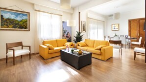 Amplia sala de estar con dos sofás amarillos, una mesa de centro de madera y un comedor con un aparador y sillas.