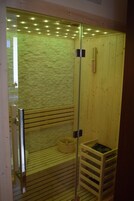 Sauna, jossa on puiset lauteet, lasiseinä ja puinen seinä.