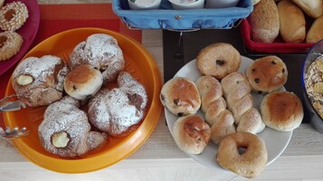Un tavolo con diversi prodotti da forno, tra cui pasticcini e panini.