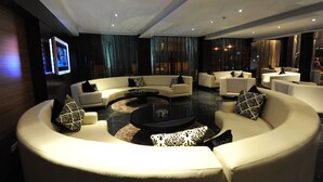 A modern living room with a curved sofa set, a central coffee table, and a flat-screen TV mounted on the wall.