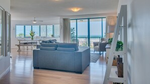 Un salón amplio con un sofá gris, una mesa de comedor y un balcón con vistas.