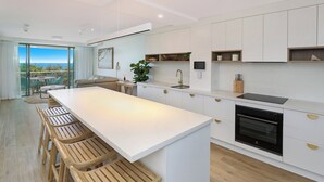 Una cocina moderna con una isla grande, taburetes de madera y vistas al exterior.