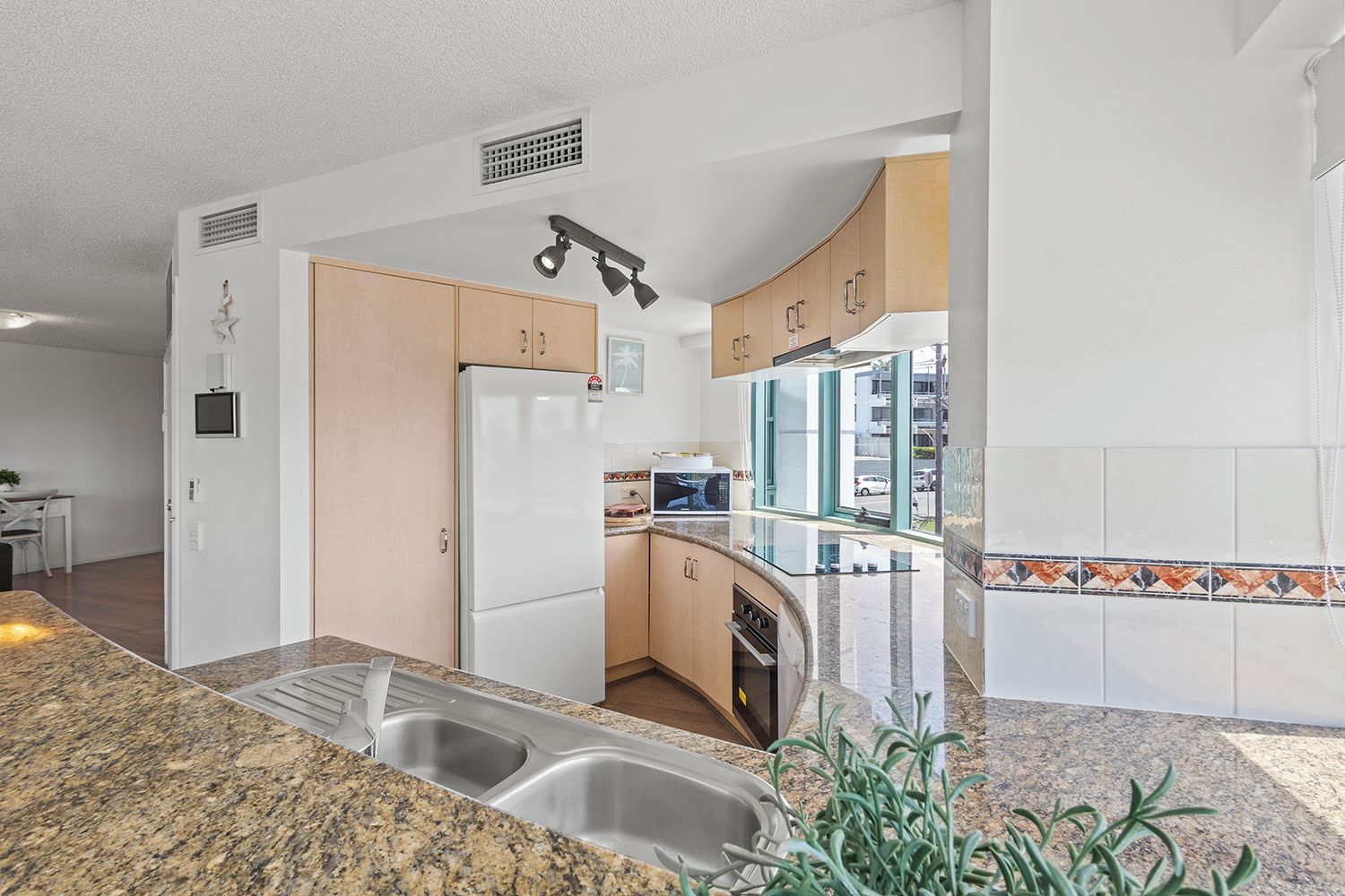 Una cocina moderna con un lavamanos doble, un refrigerador y un microondas.
