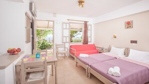 Habitación de hotel con dos camas, un escritorio con una silla, una mesita con fruta y vistas al exterior.