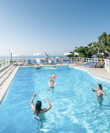 Una piscina al aire libre, sombrillas, sillones reclinables de piscina