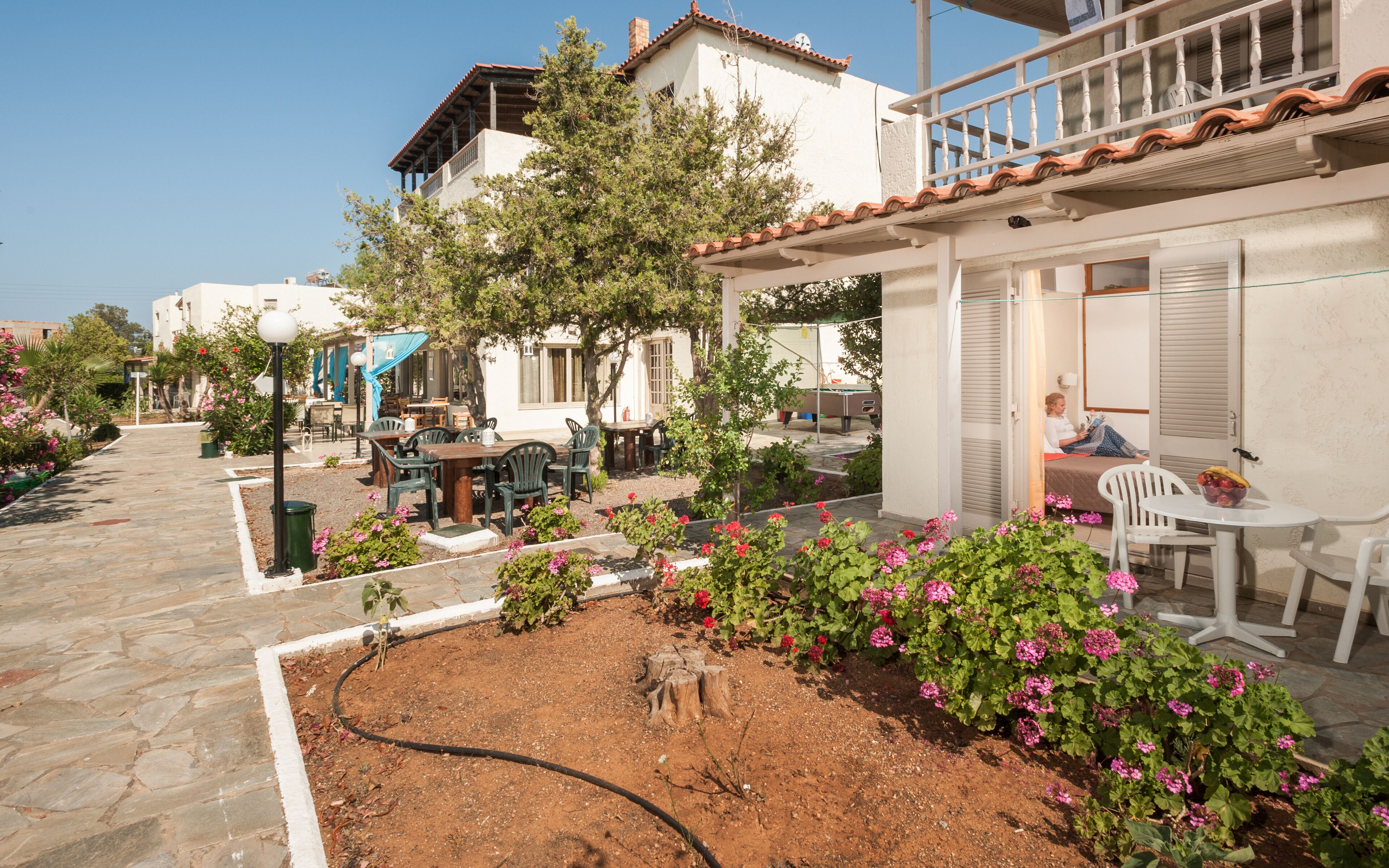 A courtyard with outdoor seating, a pool table, and a person reading.