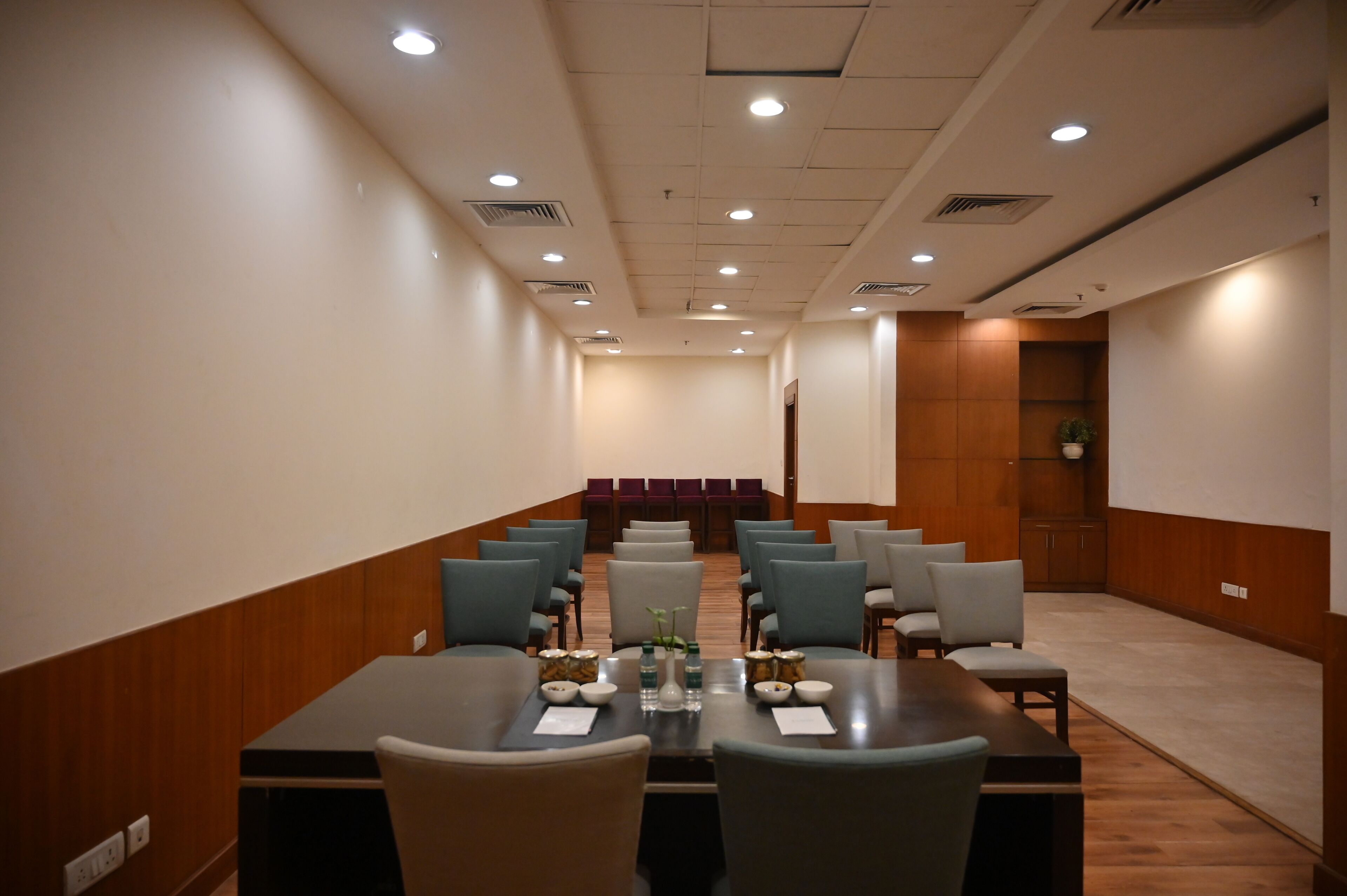 Une salle de conférence avec une longue table, des chaises et un mur décoratif en bois.