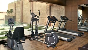 A gym with treadmills, elliptical machines, and a rowing machine. - Savoy Suites Greater Noida (Greater Noida)