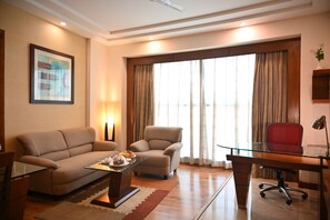 Una sala de estar moderna con un sofá, un sillón, una mesa de centro de vidrio y un escritorio con una silla.