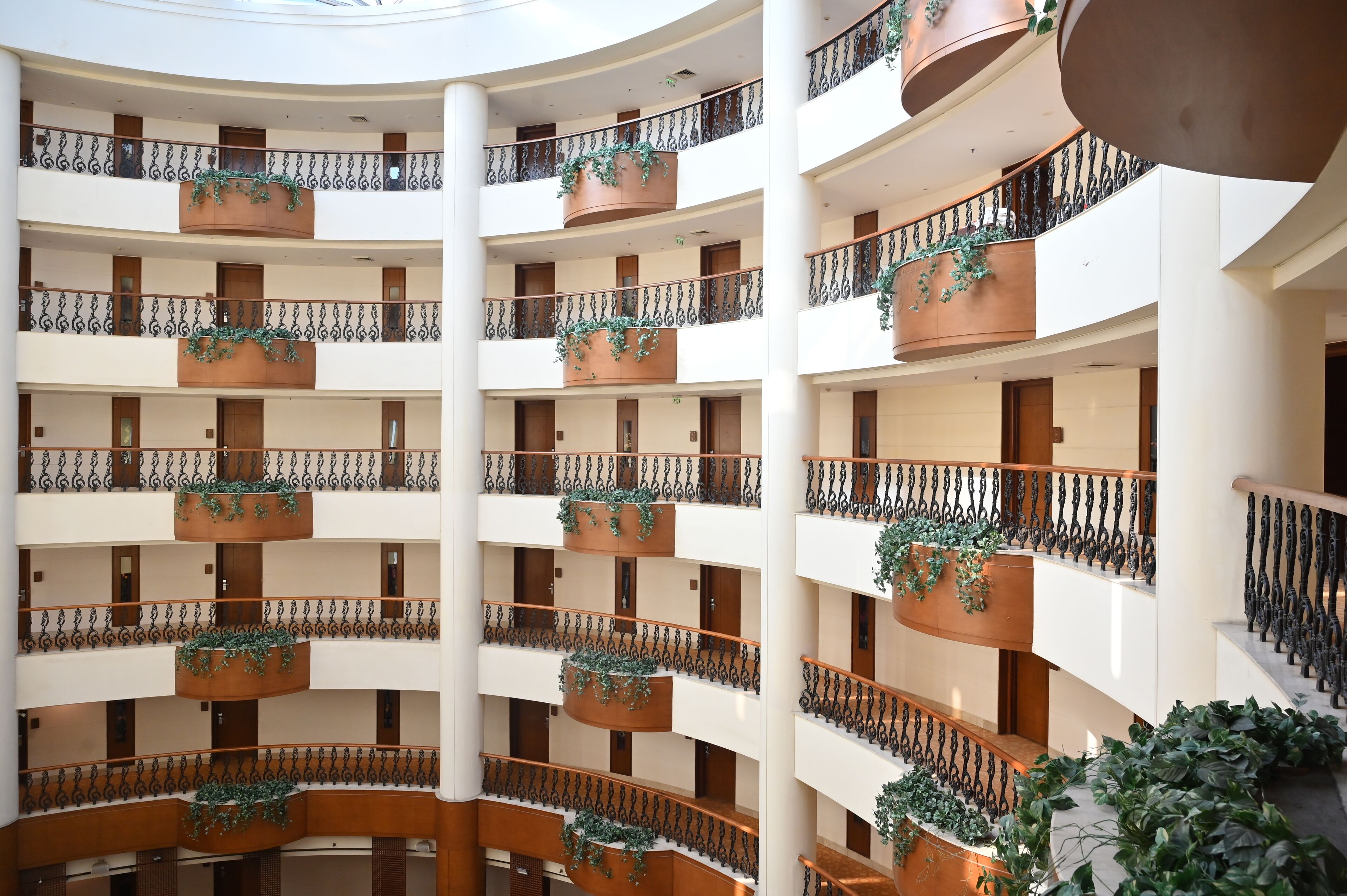Un atrium à plusieurs niveaux, doté de balcons, chacun orné de rampes en fer forgé et de plantes en pot.