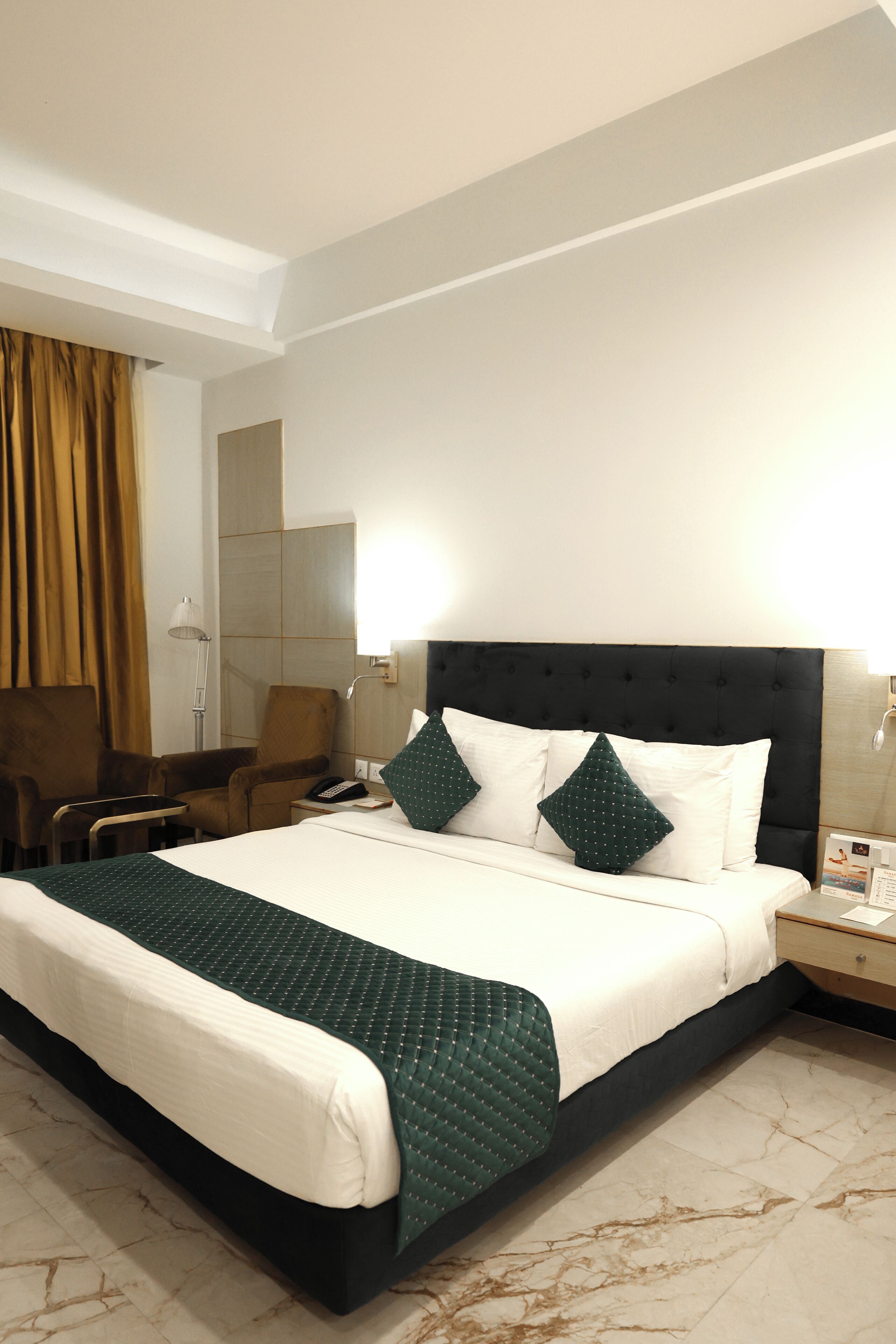 Una habitación de hotel con cama, una silla, una mesita de noche y una lámpara.