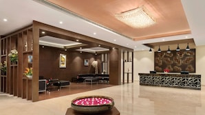 A modern lobby with a reception desk, seating area, and decorative elements like a flower arrangement and artwork. - Ramada by Wyndham Neemrana (Neemrana)