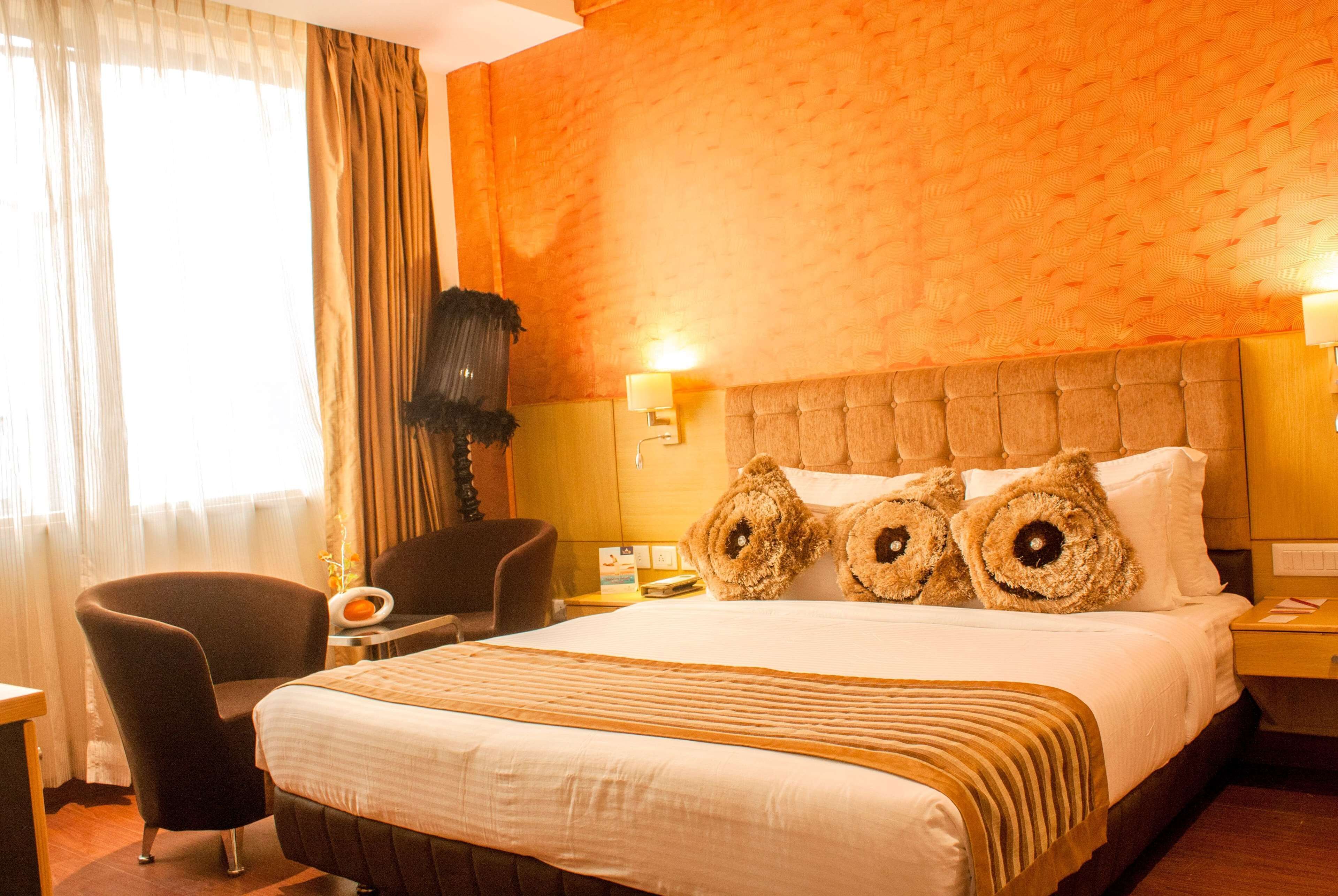 Een hotelkamer met een groot bed, een stoel, een nachtkastje en een lamp.