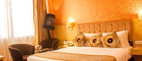 Een hotelkamer met een groot bed, een stoel, een nachtkastje en een lamp.