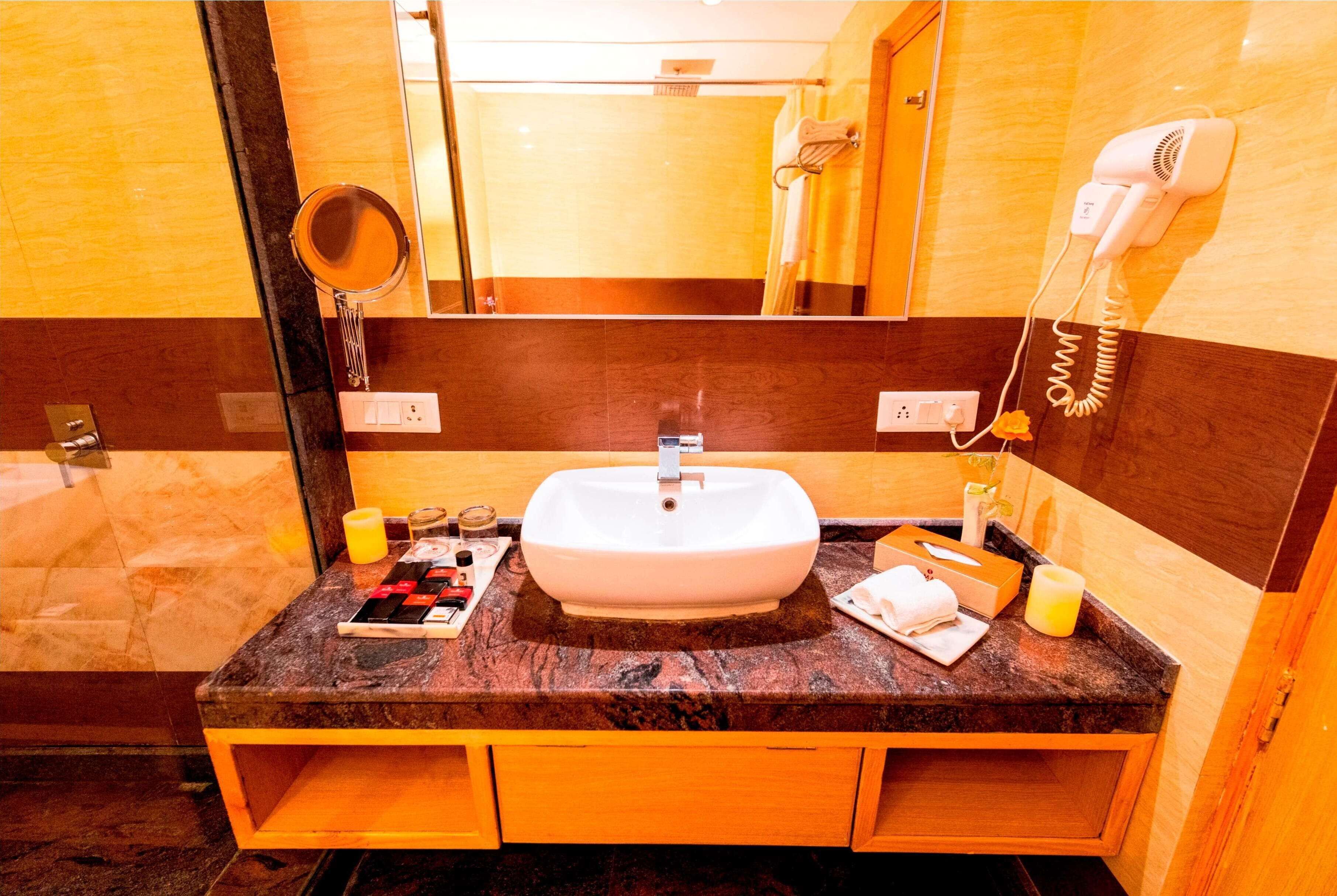 A bathroom with a marble sink, wooden cabinets, a mirror, a hairdryer, and a towel rack.