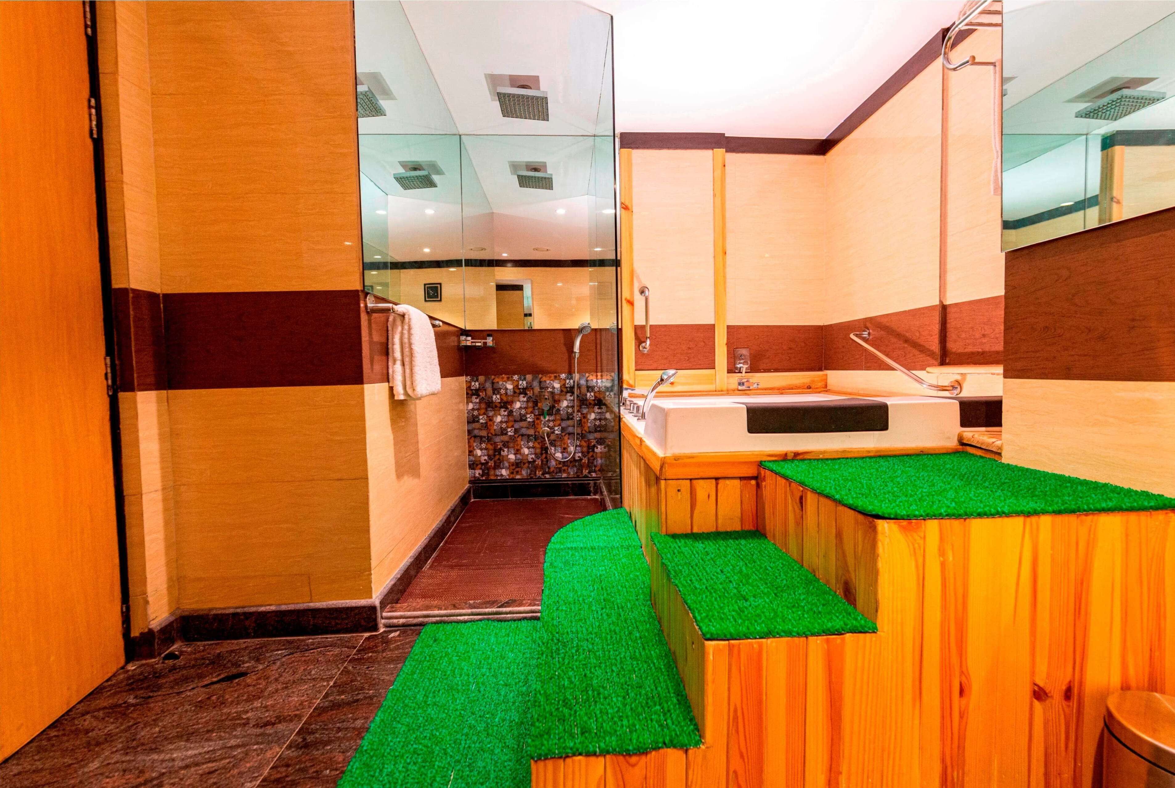 A modern bathroom with a glass partition, wooden vanity, and a green artificial grass area.