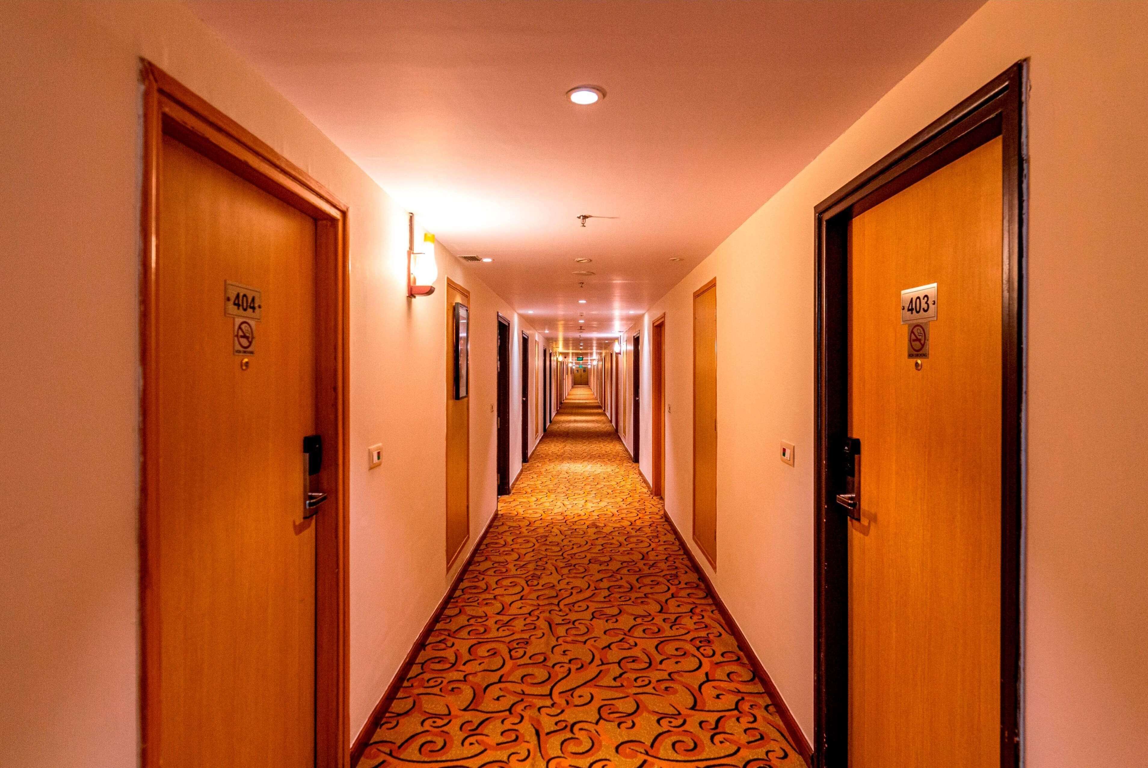 Pasillo de hotel con puertas numeradas 403 y 404, cubierto con un diseño de alfombra estampado.