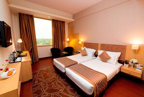 Two double beds with striped bedspreads, a desk, and a flat-screen TV.