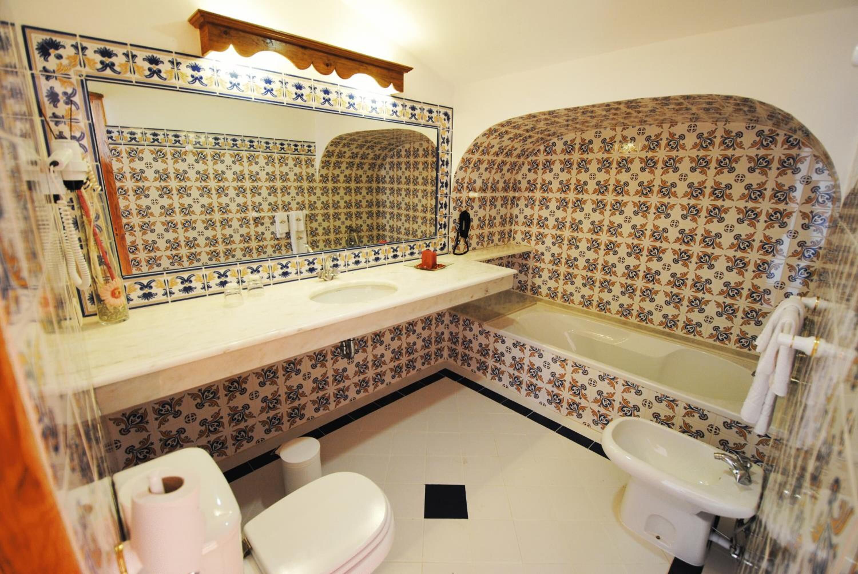 Een badkamer met een wastafel, spiegel, toilet en bad.