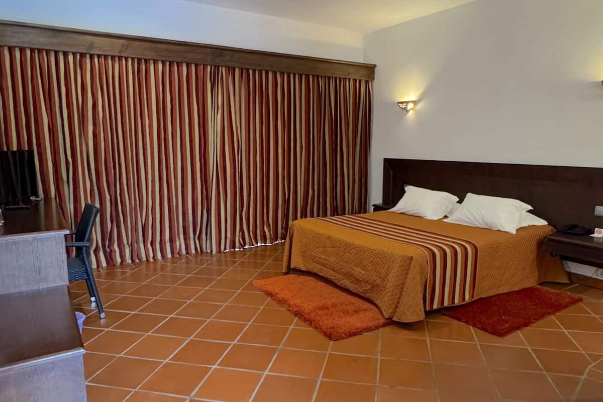 A hotel room with a bed, a desk, a chair, and a TV.