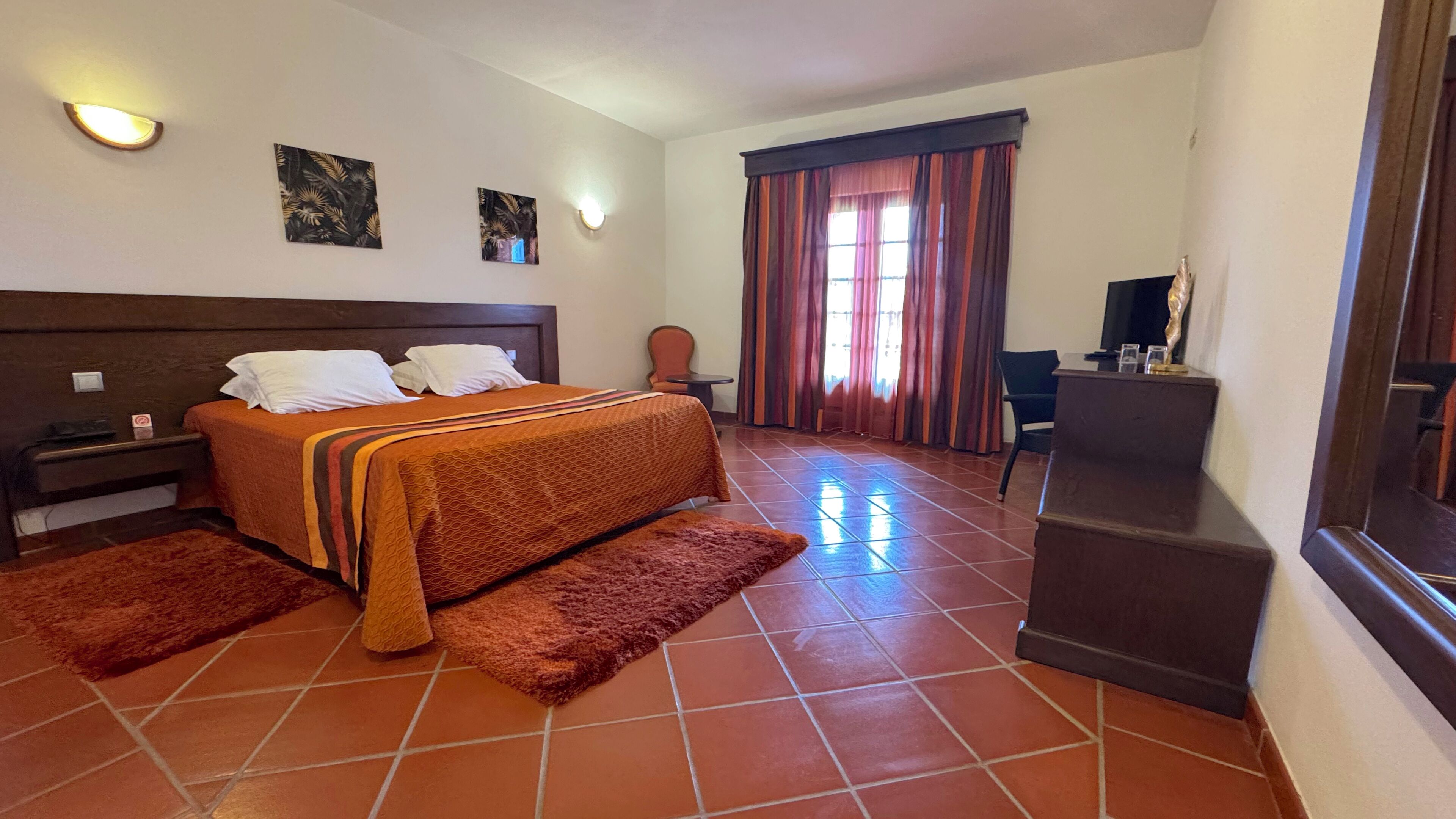 Une chambre d’hôtel avec un grand lit, un bureau, une chaise et un téléviseur.