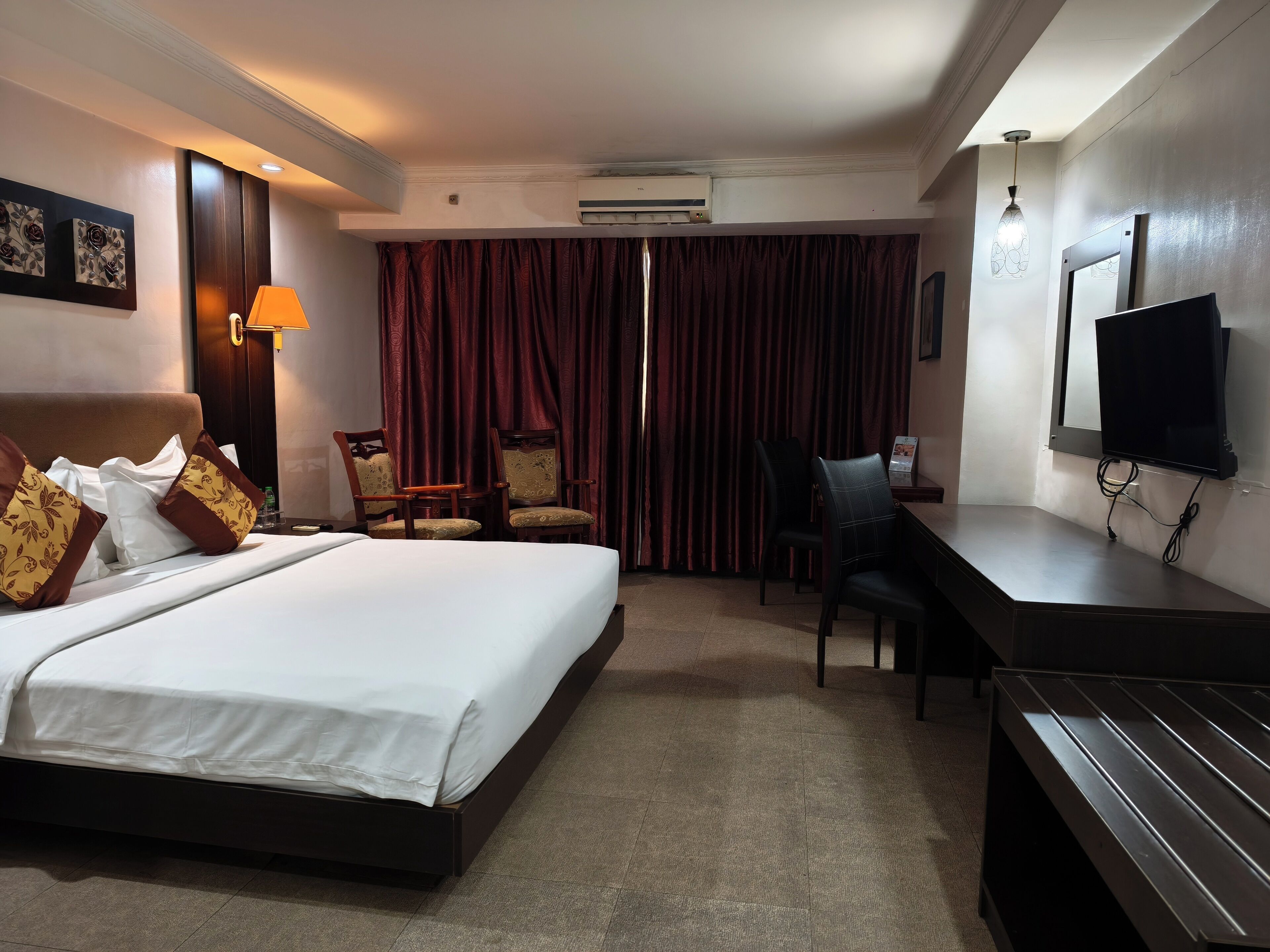 Une chambre d’hôtel avec un grand lit, deux fauteuils, un bureau, une télévision et un appareil de climatisation.