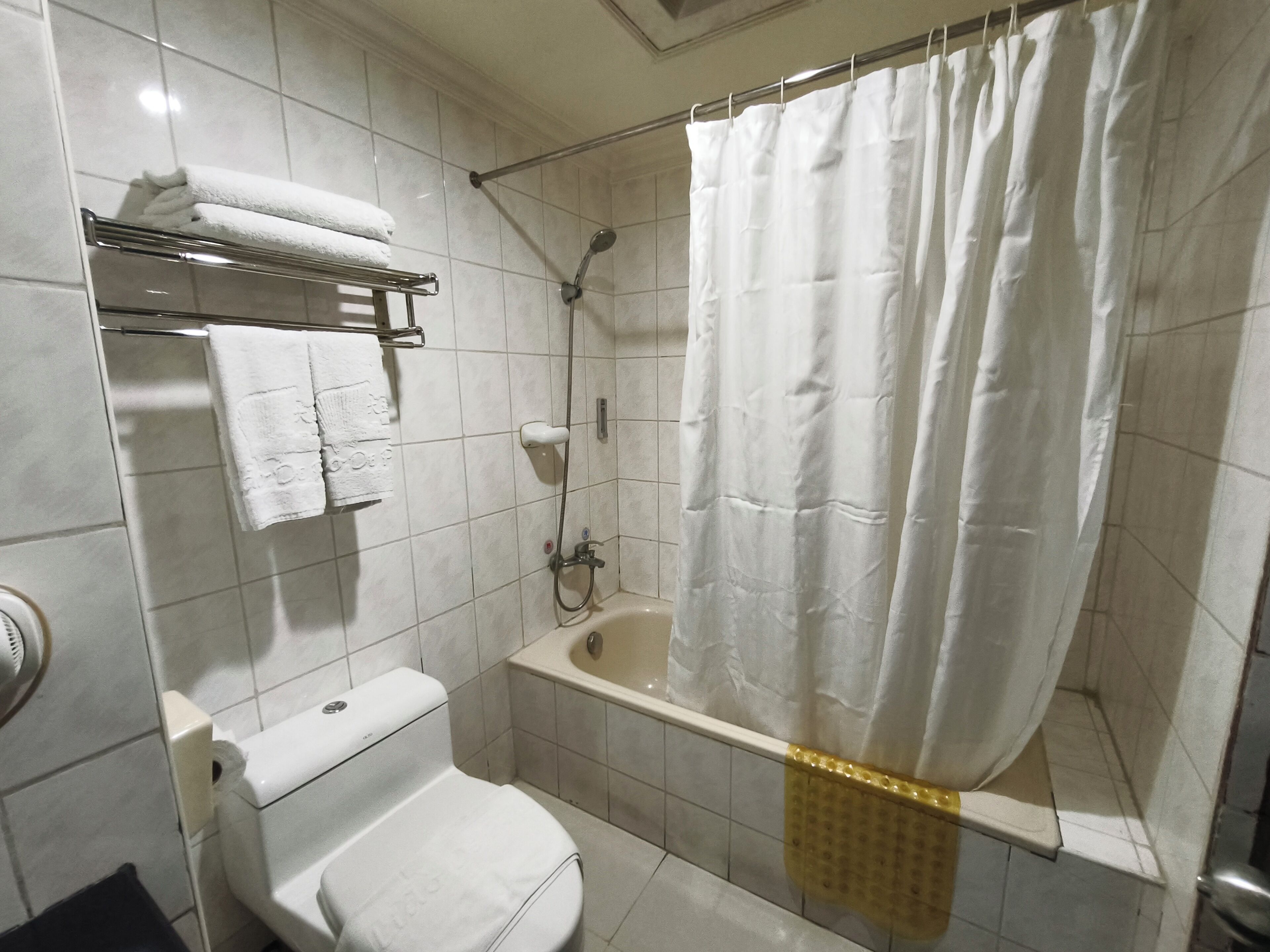 Un baño con inodoro, bañera, ducha y un perchero para toallas.