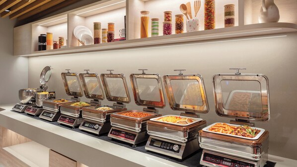 Een buffetopstelling met diverse bakken en bestek.