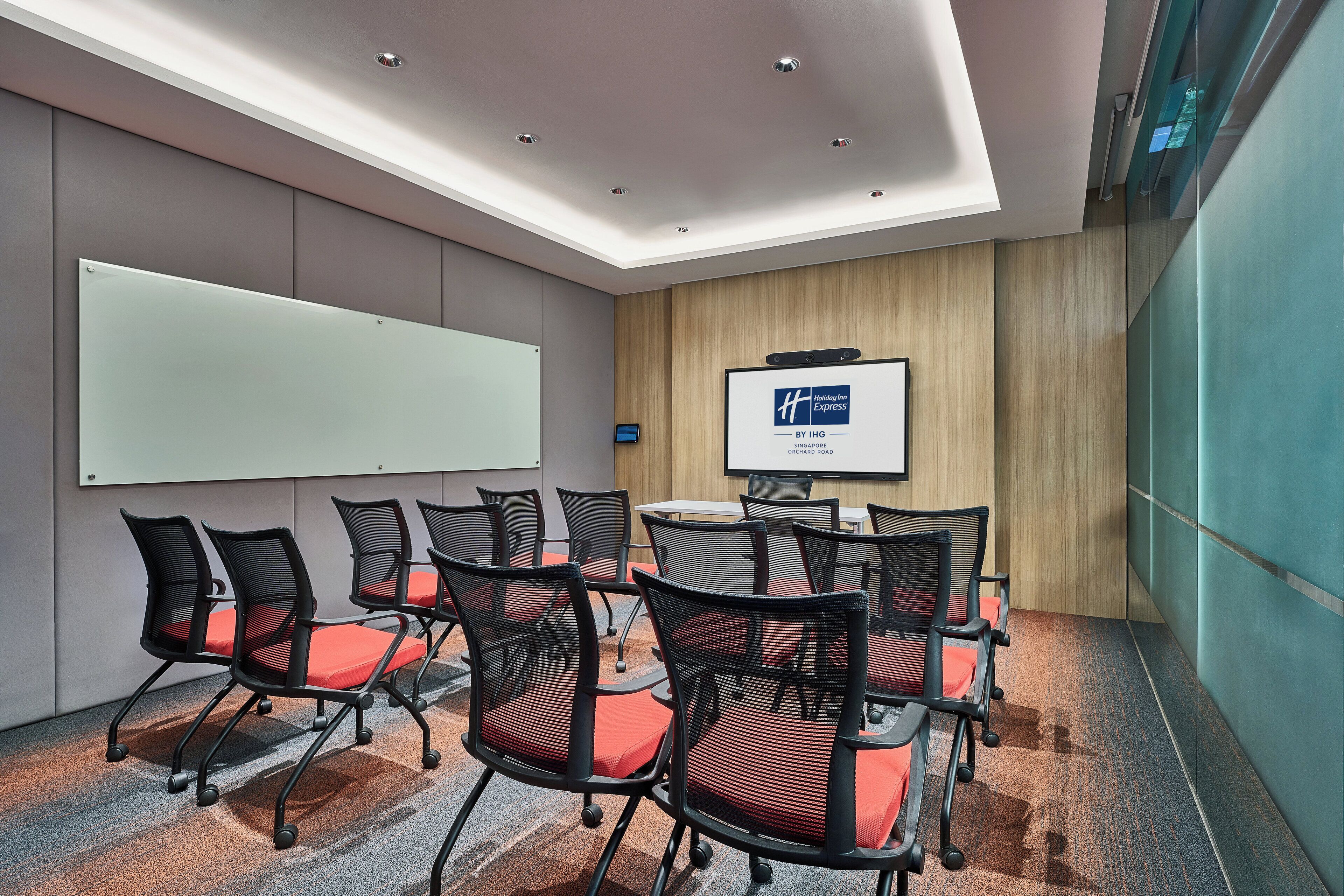 Una sala de conferencias con una pizarra, un monitor y disposición de sillas.