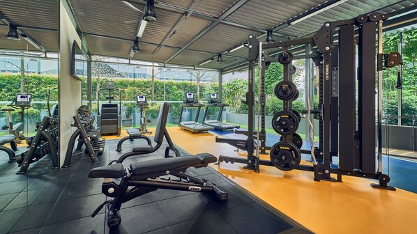 Un gimnasio con cintas de correr, máquinas de pesas y pesas sueltas.