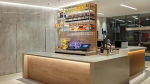 En modern receptionsdisk med träinredning, ett vitrinskåp i glas med olika flaskor och en digital informationskiosk.