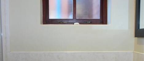 A bathroom with a white sink, a window with frosted glass panes, and a tiled backsplash.