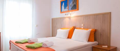 Habitació d'hotel amb un llit, una taula de nit, un quadre a la paret i una finestra amb cortines.