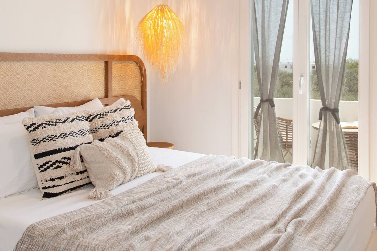 A bedroom with a wooden ceiling, a bed with a patterned blanket, and a hanging light fixture.