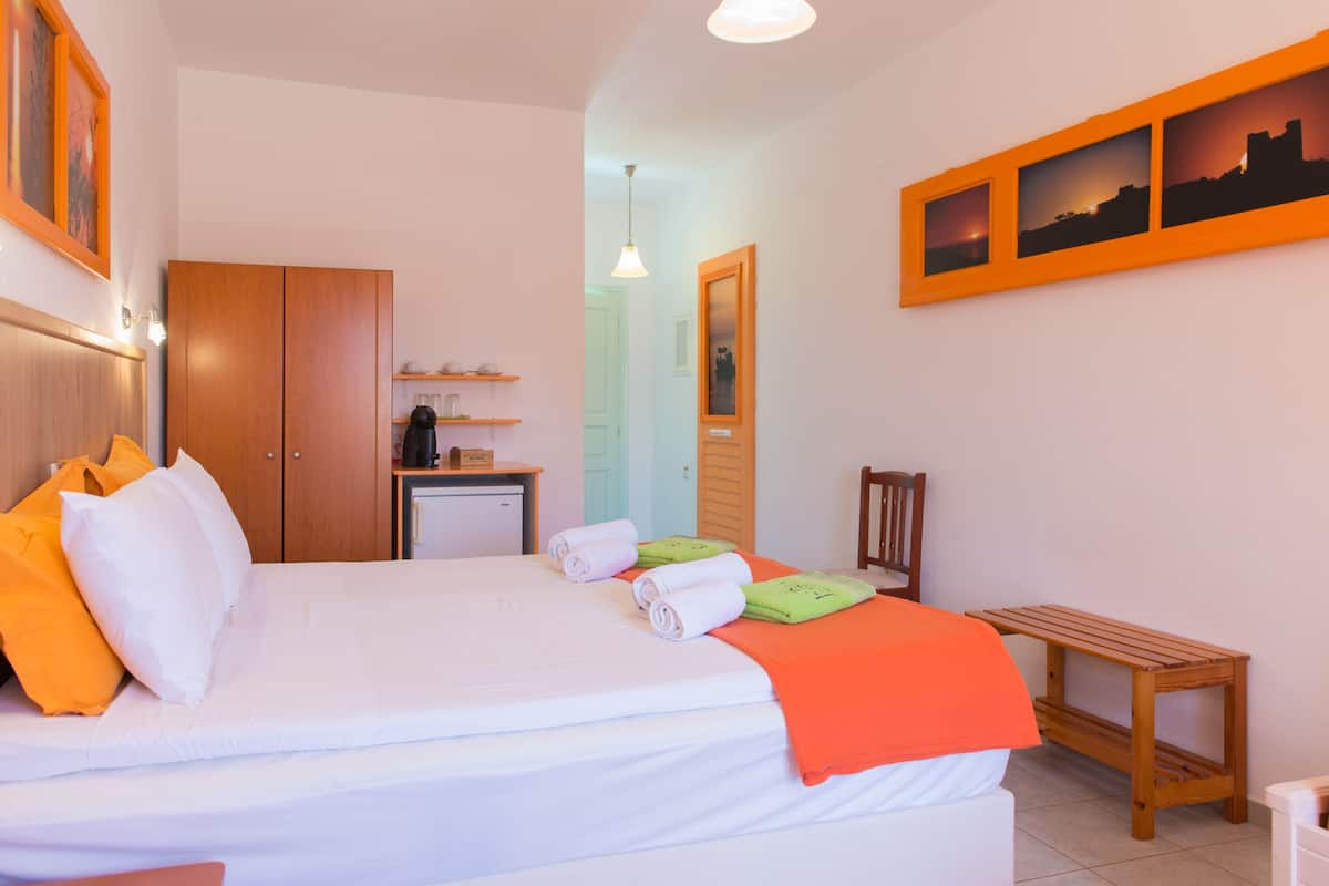 A hotel room with a bed, a desk, a chair, and a small table.