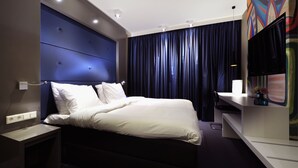 Et moderne hotelværelse med en stor seng, et fladskærms-tv og et skrivebord.