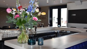 Et moderne køkken med en central ø, en blomstervase og et glas vand på bordet.