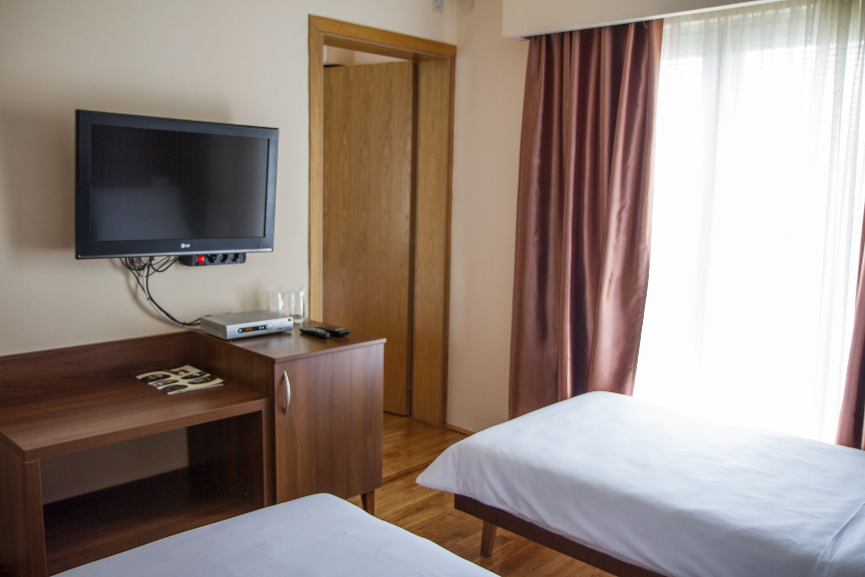 Habitación de hotel con cama, escritorio y televisión, y una puerta.