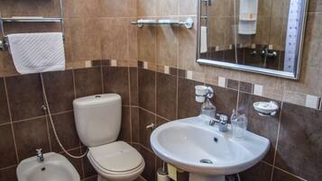 Un baño con inodoro, bidé, lavabo y espejo.