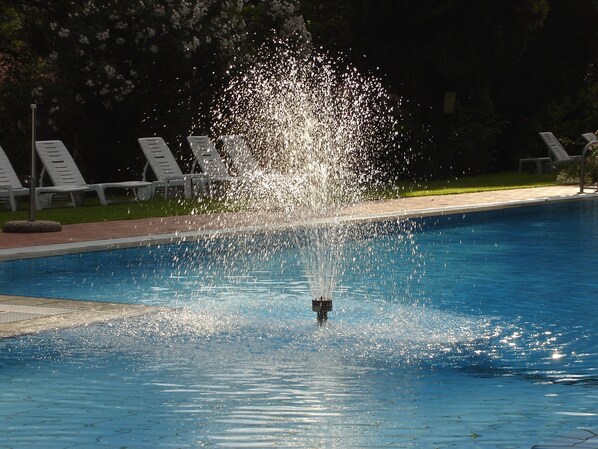 Una piscina al aire libre de temporada, sombrillas, tumbonas