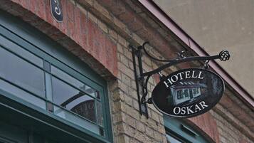 A hotel sign with the name "HOTELL OSKAR" and a number "3" above it, mounted on a brick building.