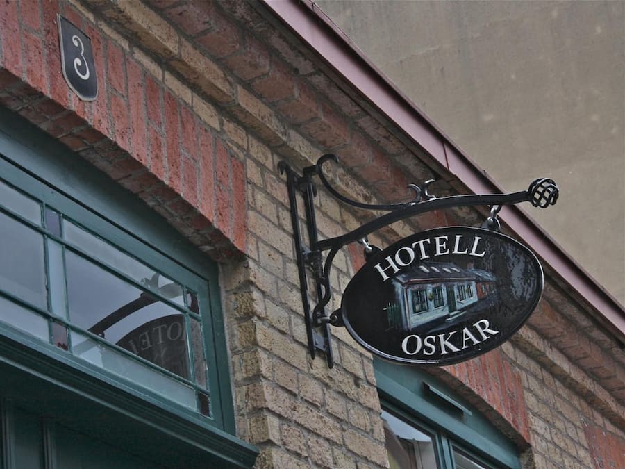 A hotel sign with the name "HOTELL OSKAR" and a number "3" above it, mounted on a brick building.