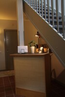 A reception desk with a plant, a lamp, and a sign.