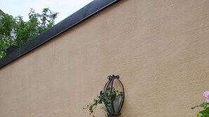 A stone bench and a wall-mounted lantern in a garden area. - Hotell Oskar (Lund)