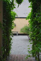 Un sendero de grava que lleva a un banco y un edificio con pared amarilla.