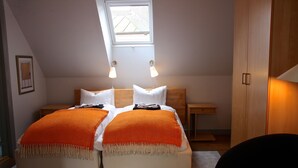 A bedroom with two beds, a skylight, bedside lamps, and a nightstand. - Hotell Oskar (Lund)